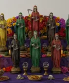 Cómo crear un espacio sagrado sin necesidad de un ritual costoso: Altar escalonado con estatuas de la Santa Muerte en diversos colores, rodeadas de velas, flores y objetos rituales.
