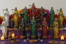 Cómo crear un espacio sagrado sin necesidad de un ritual costoso: Altar escalonado con estatuas de la Santa Muerte en diversos colores, rodeadas de velas, flores y objetos rituales.